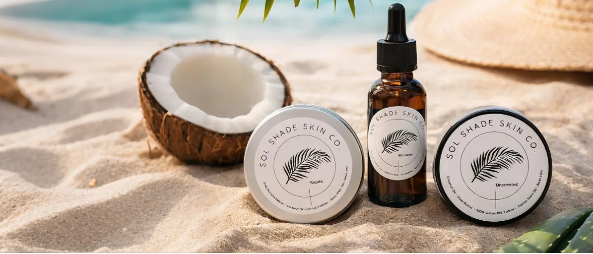 Skincare products from Boi Prince Skin Co on a sandy beach with a coconut and seashell.